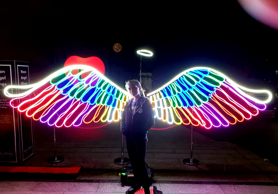 Photo shows my daughter Boo, standing in front of neon angel wings