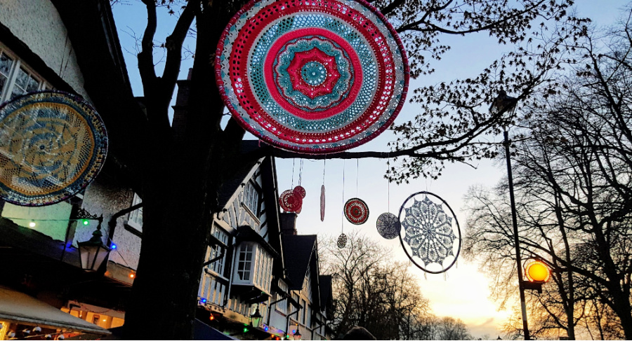 a selection of crochet mandalas hanging from trees in the twilight.