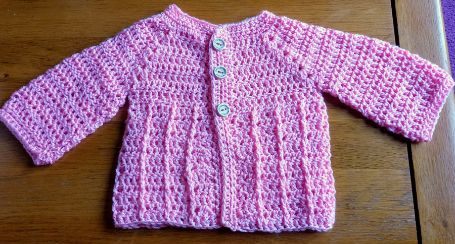 baby cardigan in pink from the front with arms out 