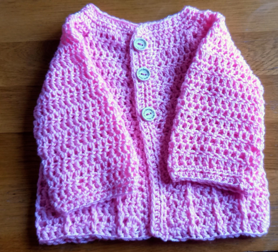 baby cardigan in pink with arms folded in