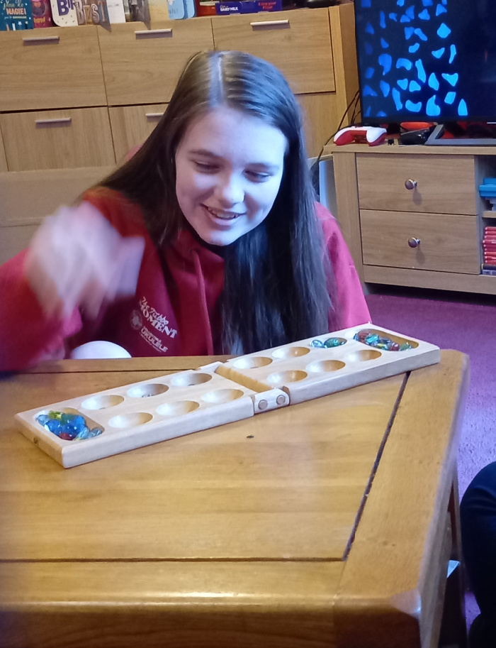 My daughter in front of a mancala set moving the marbles 