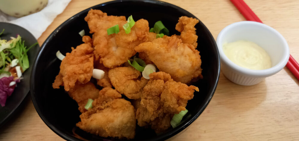 karaage chicken in a black bowl served with Japanese mayonnaise