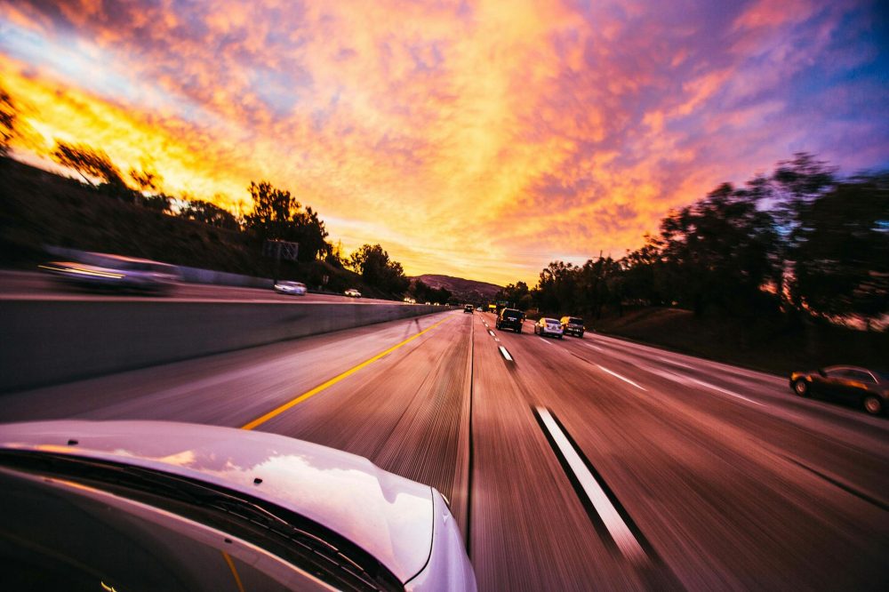 driving music, view of a car bonnet driving into a sunset